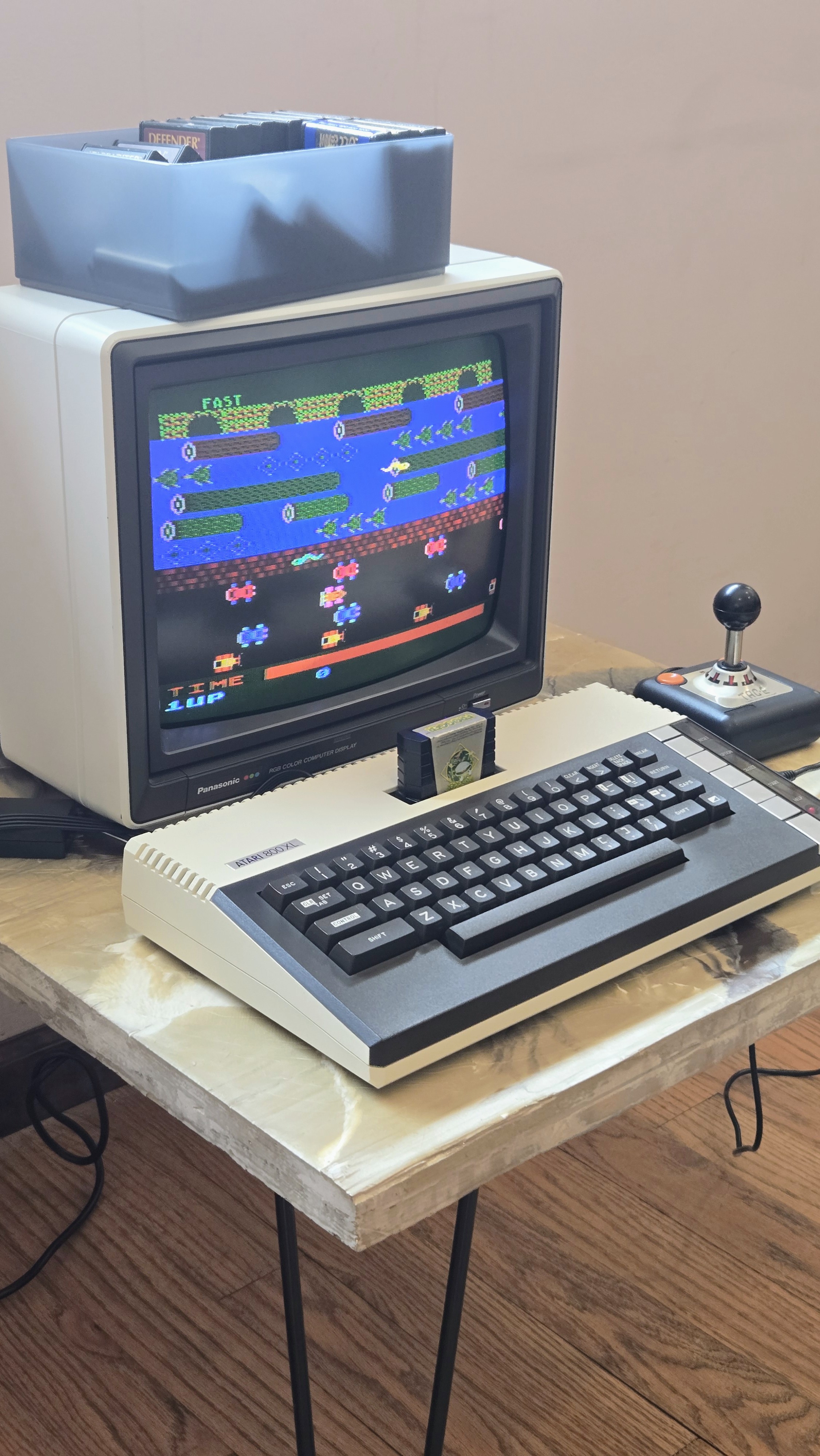 Atari 800XL running Frogger on a Panasonic RGB monitor, with a bin of cartridges and a joystick