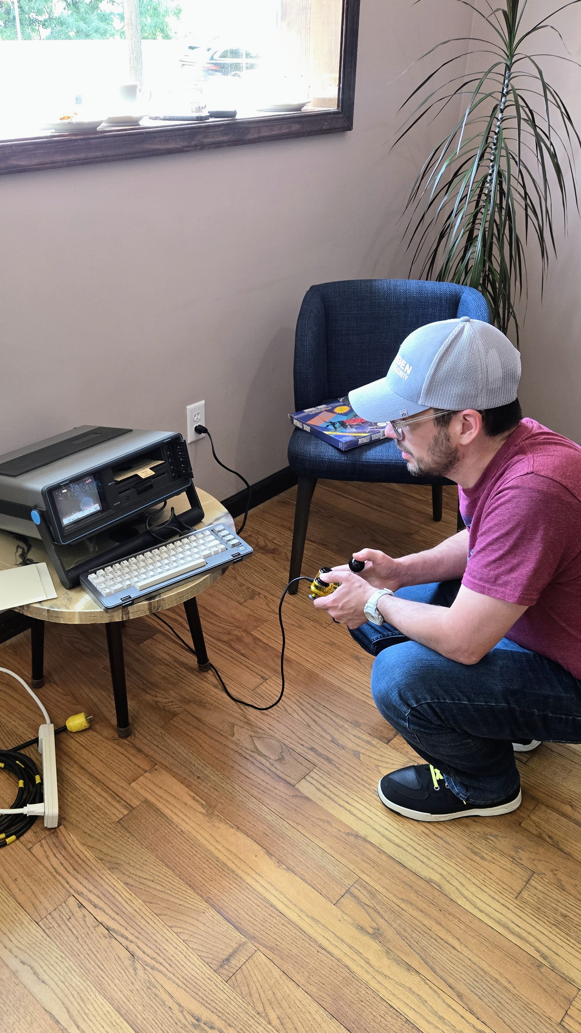 Member with a joystick playing Pitfall on a Commodore SX-64 portable